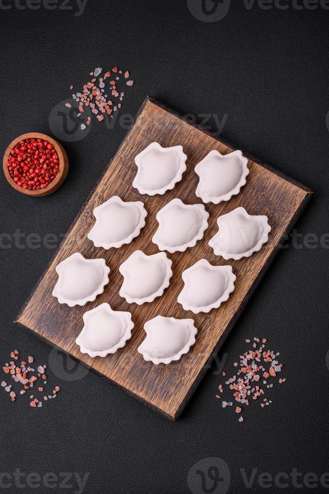 Raw frozen stuffed dumplings on a wooden cutting board photo