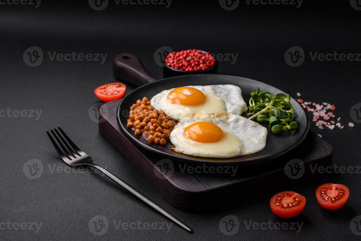 delicioso abundante desayuno consistente de dos frito huevos, Enlatado lentejas y microgreens foto