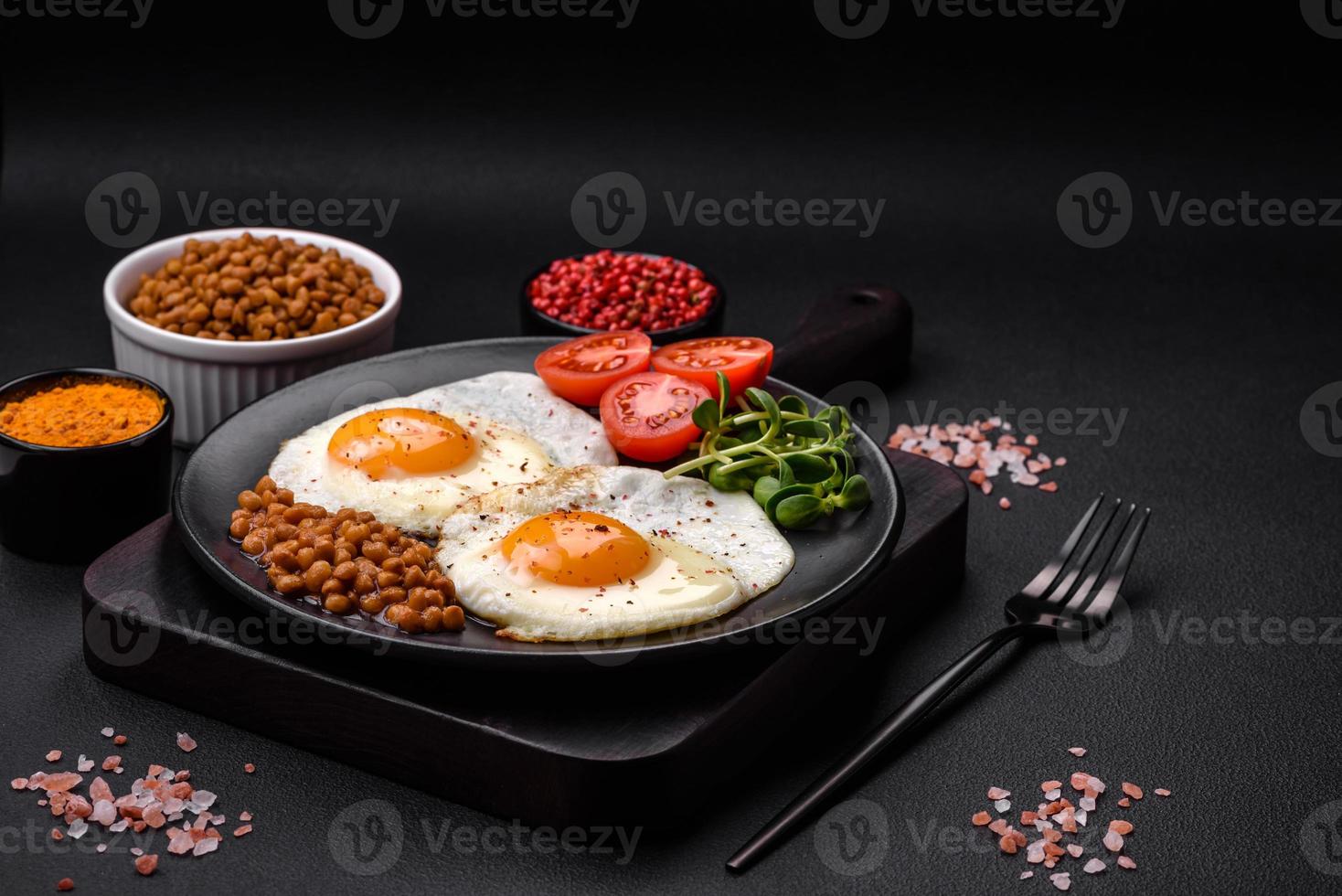 delicioso abundante desayuno consistente de dos frito huevos, Enlatado lentejas y microgreens foto