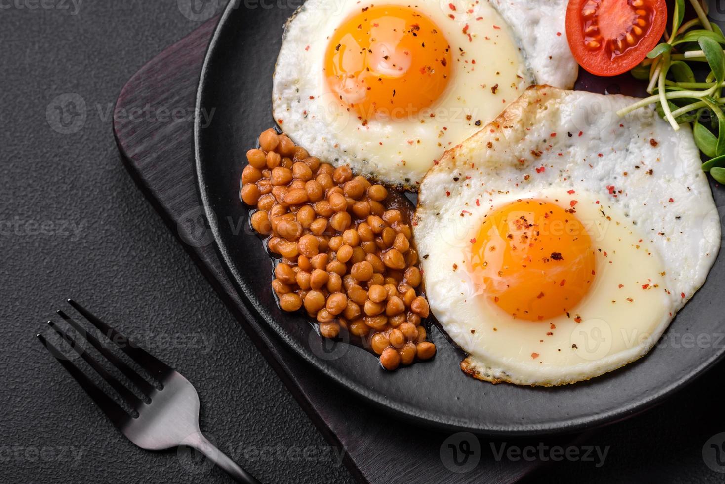 Delicious hearty breakfast consisting of two fried eggs, canned lentils and microgreens photo