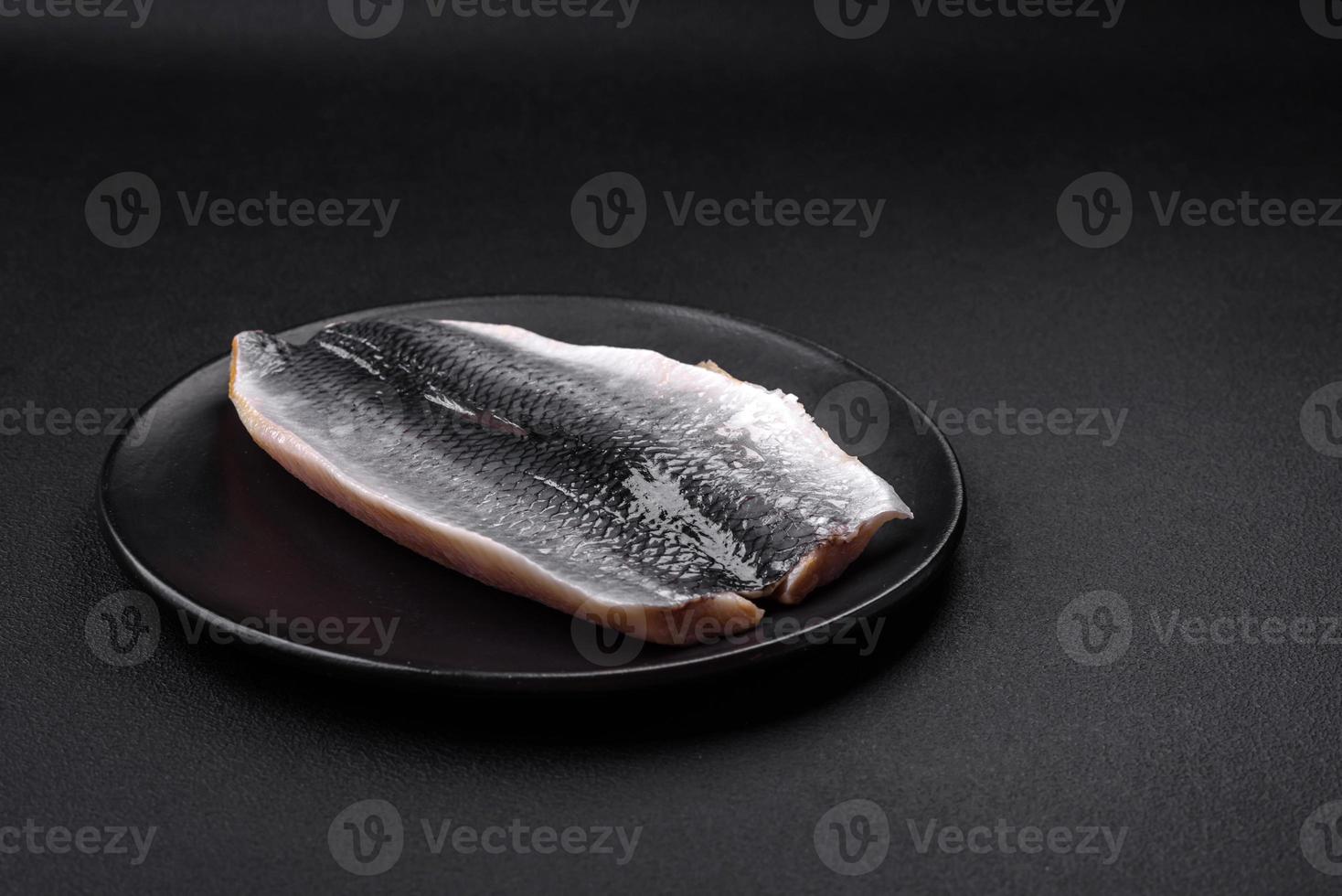 Delicious salted herring fillet in oil on a black ceramic plate photo