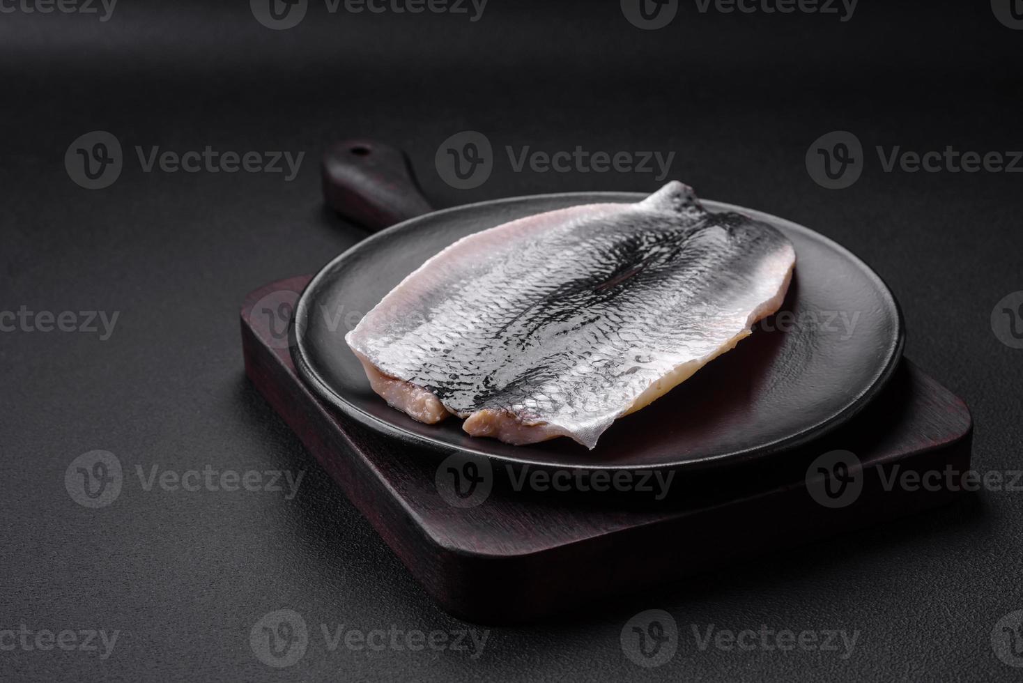 Delicious salted herring fillet in oil on a black ceramic plate photo