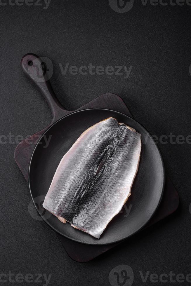delicioso salado arenque filete en petróleo en un negro cerámico plato foto