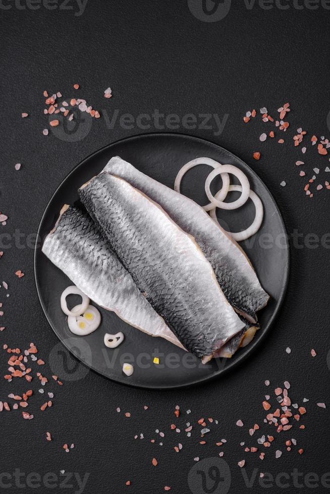 Delicious salted herring fillet in oil on a black ceramic plate photo