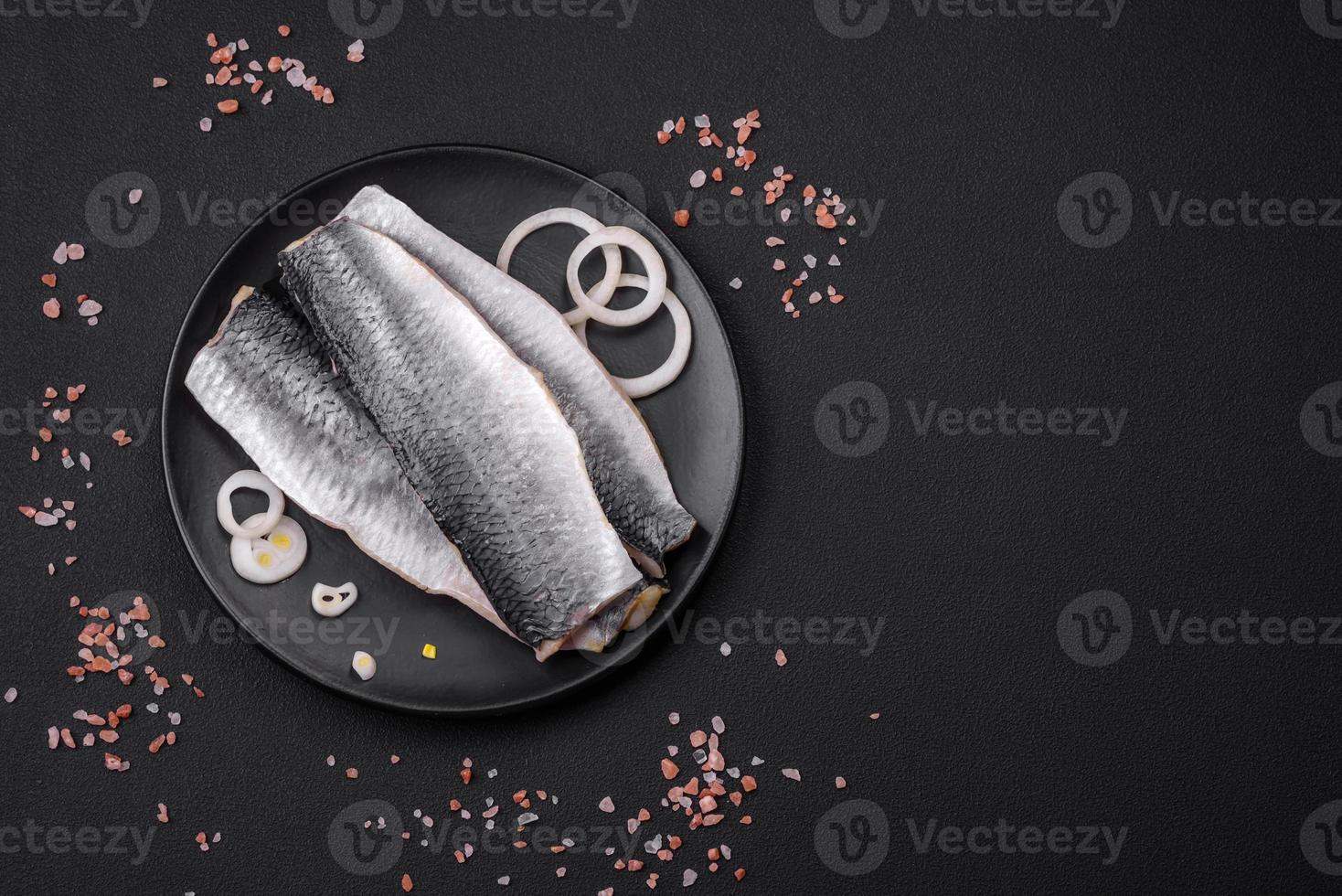 Delicious salted herring fillet in oil on a black ceramic plate