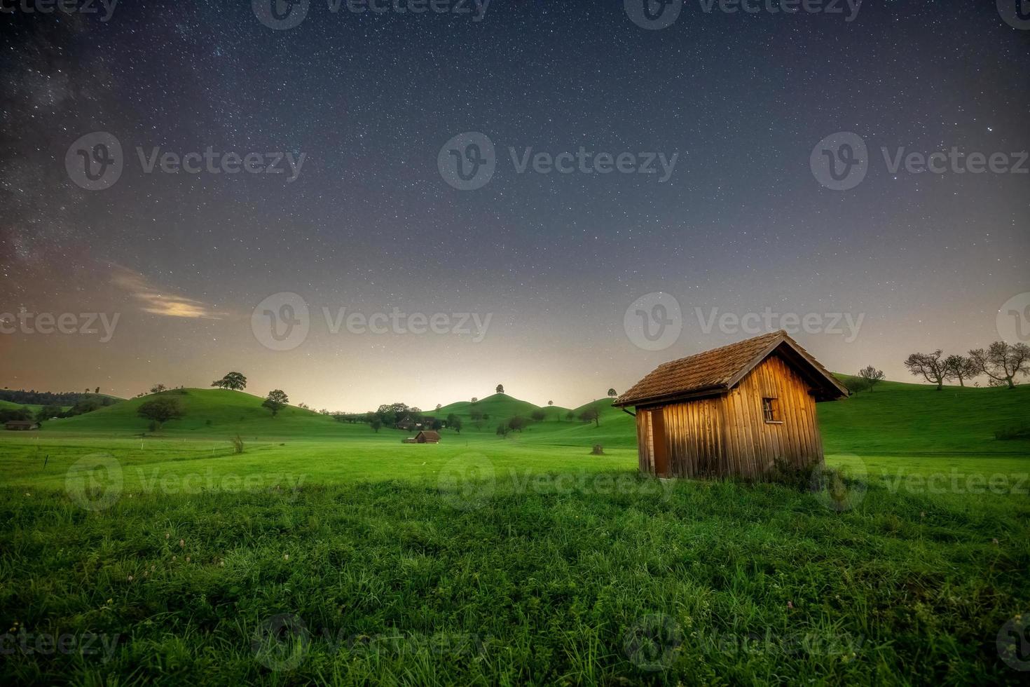 a small hut stands on a meadow sky the milky way can be seen photo