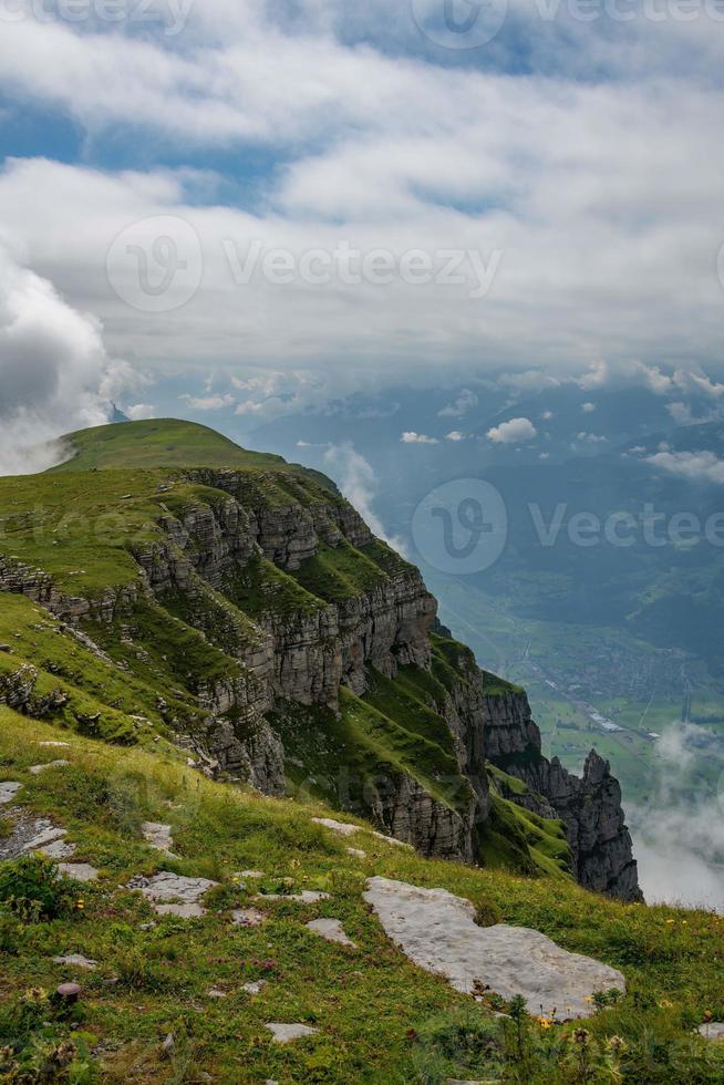 A steep cliff overgrown with grass under a cloudy sky photo