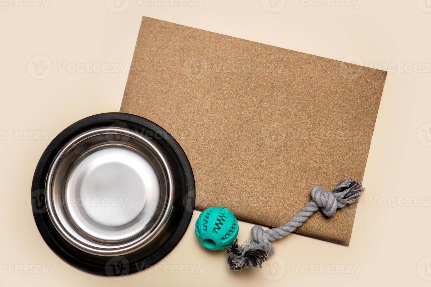 dog bowl for food and toys with blank brown sheet for text on beige background with copy space, pets photo