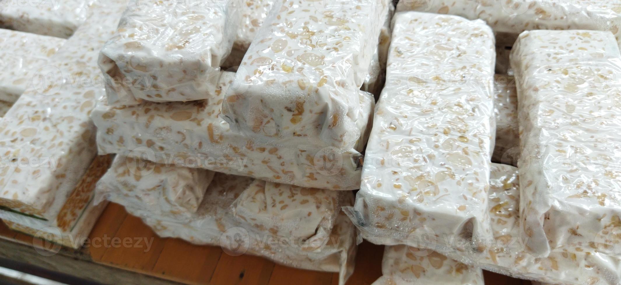 tempe mentah. raw tempeh, uncooked soybean cake from indonesia in a plastic on the table photo