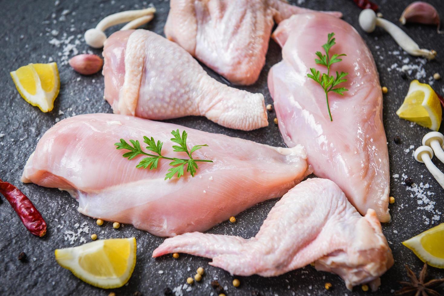 fresh raw chicken with mushroom lemon chilli herbs and spices on plack plate - Breast wings and legs uncooked chicken meat marinated with ingredients for cooking photo