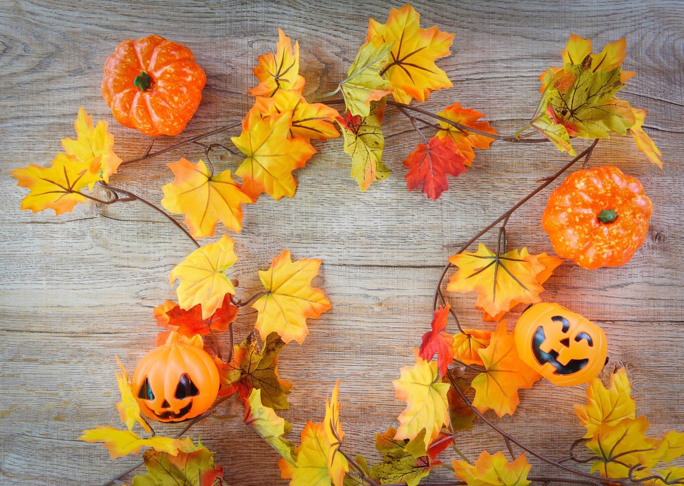 halloween background with dry leaves autumn on wooden decorated holidays festive concept - jack o lantern pumpkin halloween decorations for party accessories object , top view flat lay photo