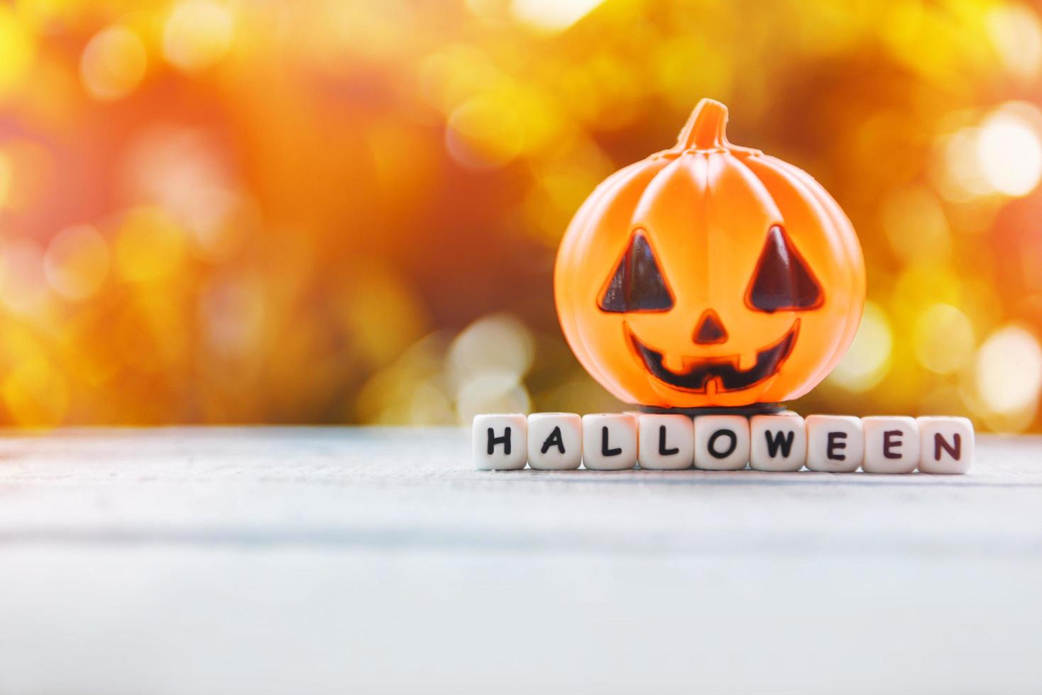 Halloween background decorated holidays festive concept - funny faces jack o lantern pumpkin halloween decorations for party accessories object  on wood orange bokeh photo