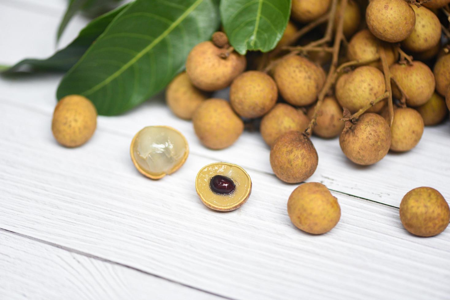 Longan fresh tropical fruit and green leaf in Thailand - Dimocarpus longan and peel exotic fruits on white wooden background photo