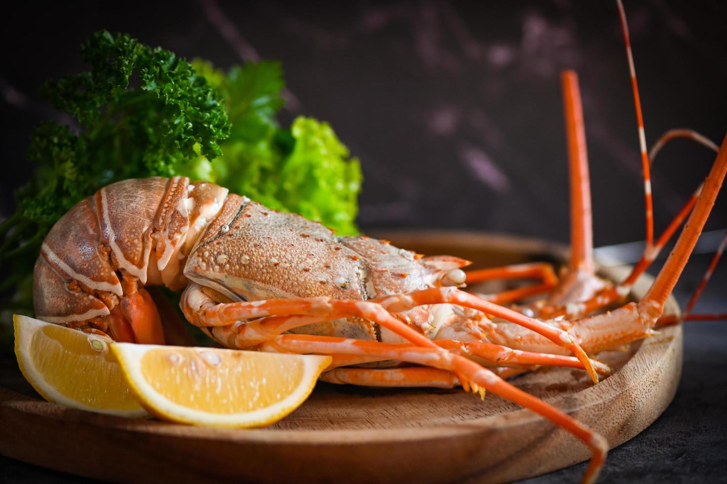 espinoso langosta Mariscos en de madera lámina, Fresco langosta o rock langosta con hierba y especias limón cilantro perejil en oscuro fondo, langosta para Cocinando comida foto