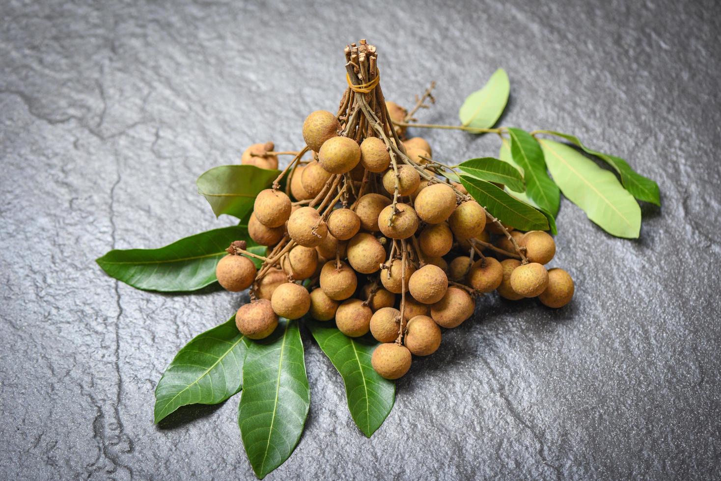 Longan fresh tropical fruit and green leaf in Thailand - Dimocarpus longan exotic fruits on black plate background photo