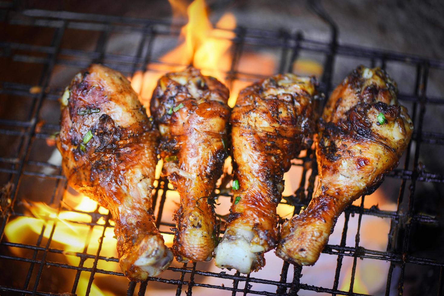 Grilled chicken legs barbecue with herbs and spices top view - Tasty chicken legs on the grill with fire flames marinated with ingredients cooking photo