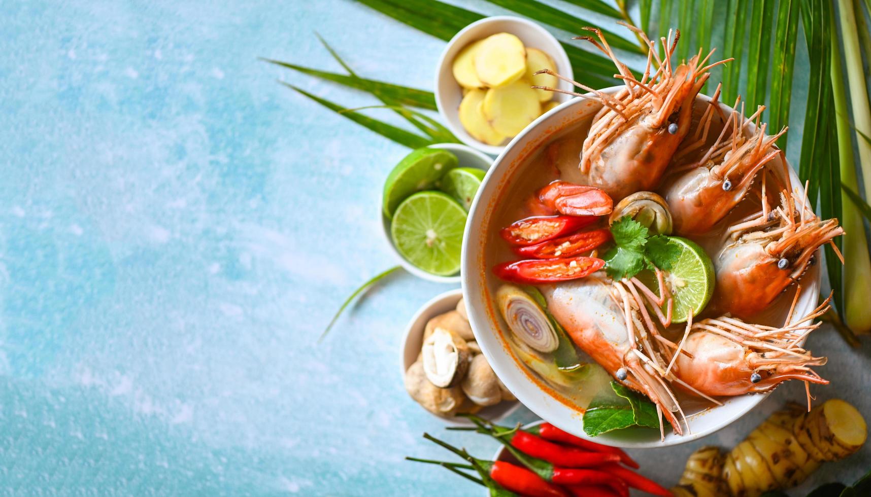 Shrimp soup on seafood soup bowl with thai herb and spices, Hot and sour spicy shrimps prawns soup  curry lemon lime galangal red chili straw mushroom on table food, Thai Food Tom Yum Kung photo