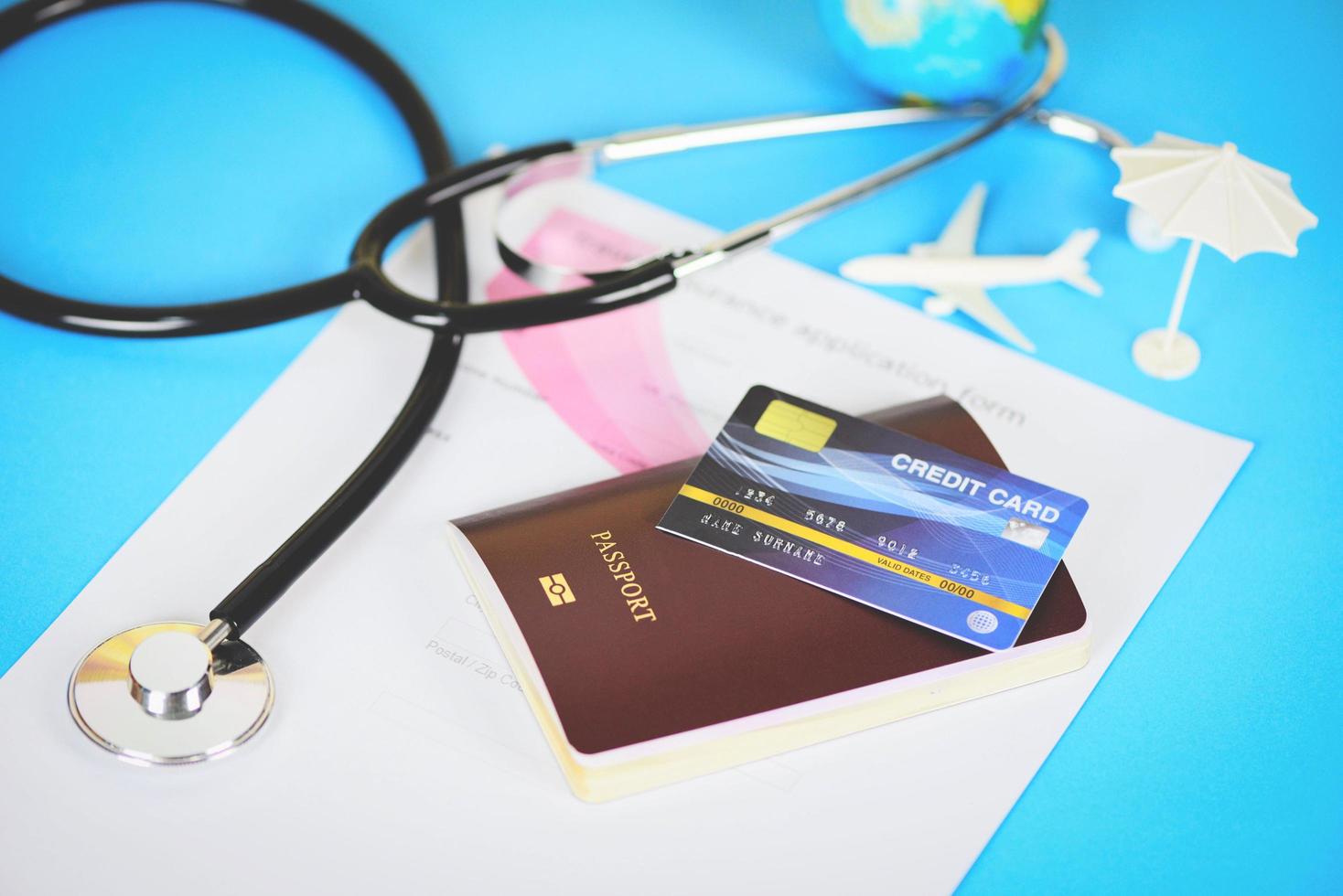 viaje seguro solicitud formar con pasaporte crédito tarjetas y estetoscopio en azul antecedentes - aire de viaje para salud o global cuidado de la salud concepto foto