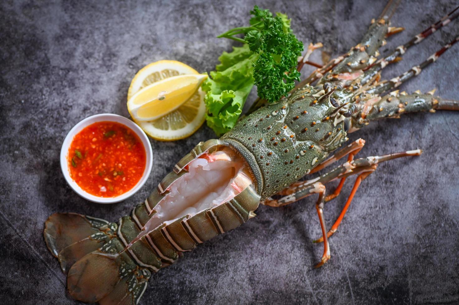 spiny lobster sashimi seafood, fresh lobster or rock lobster with herb and spices lemon parsley on dark background, raw spiny lobster for cooking food photo