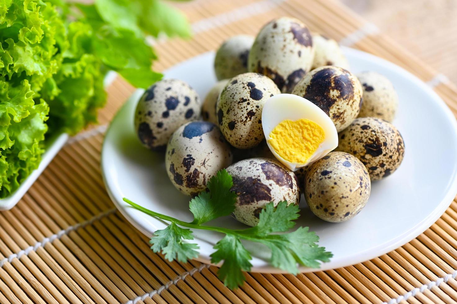 boiled eggs food, quail eggs on white plate, breakfast eggs with fresh quail eggs and vegetable coriander on wooden table background photo