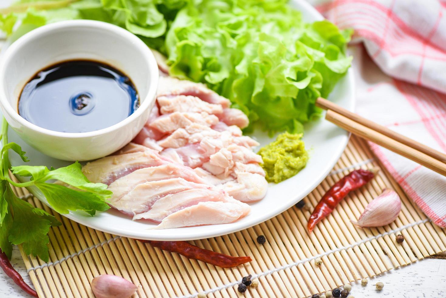 Sashimi raw chicken on white plate with wasabi sauce and vegetable salad garlic chilli herbs and spices traditional japanese food - chicken slices meat fillet photo