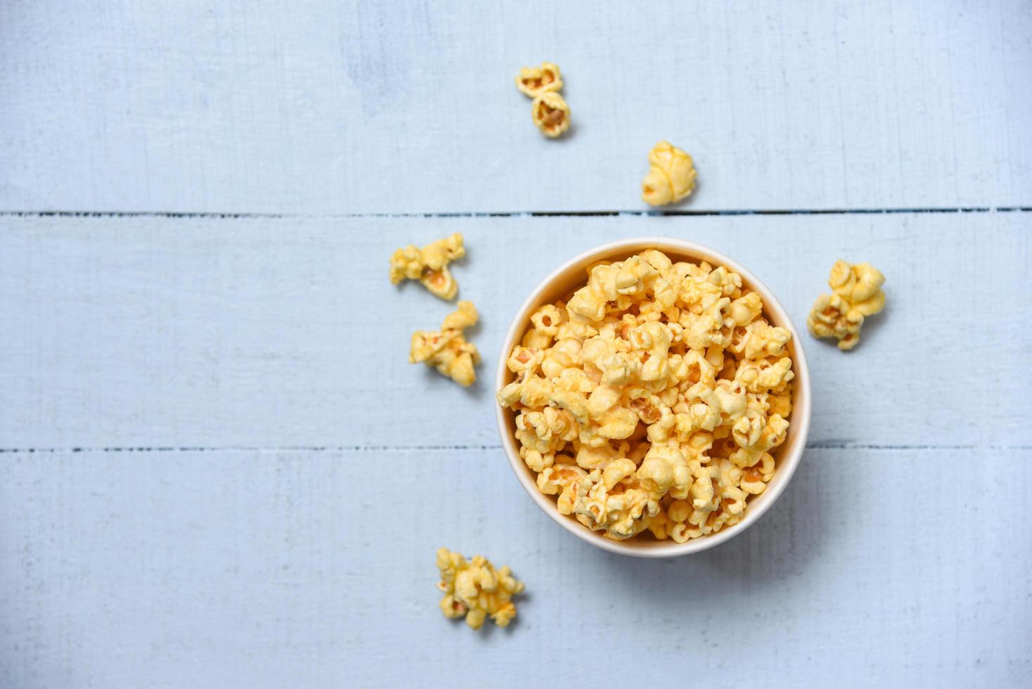 Sweet butter popcorn in bowl on wooden photo