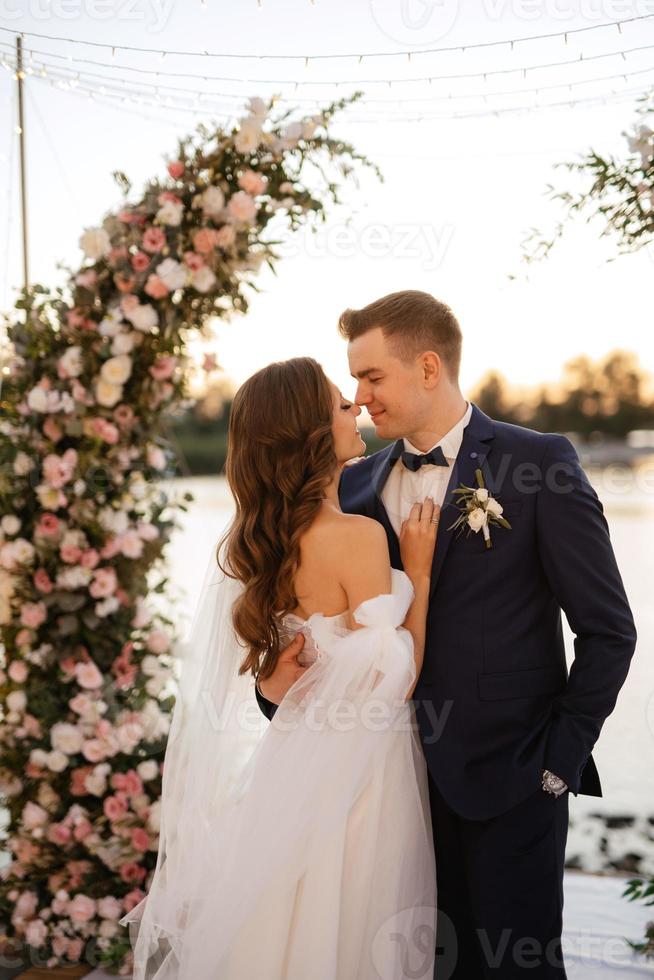 novia y novio contra el telón de fondo de una puesta de sol amarilla foto