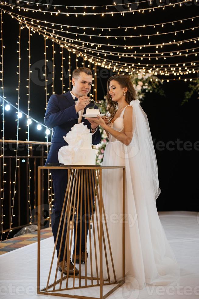 newlyweds happily cut and taste the wedding cake photo
