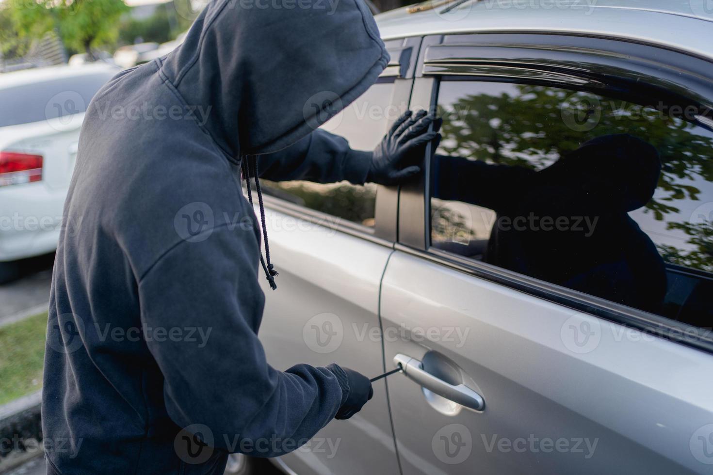 Robber breaking into a car at the parking lot. photo