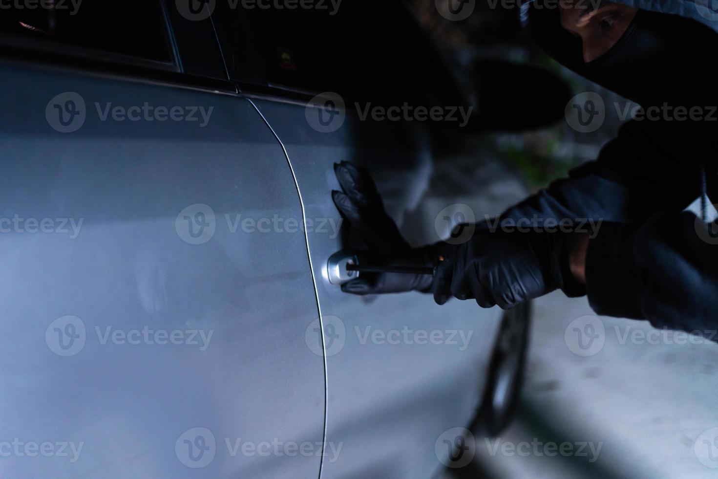 Car thief using a tool to break into a car photo