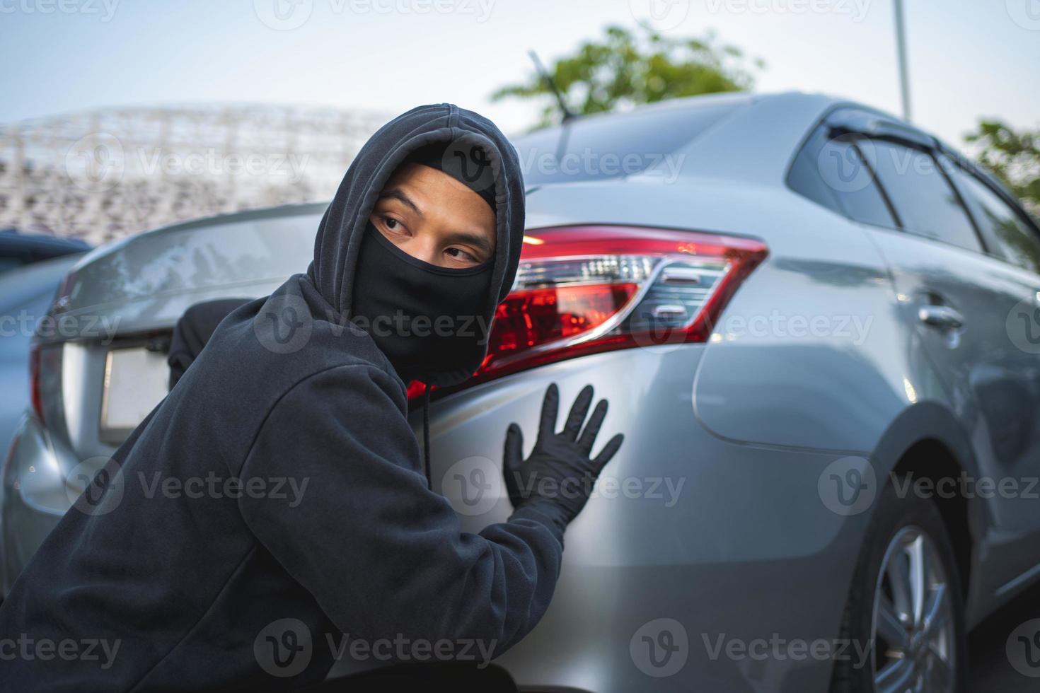 Masked thief in action before burglary. Car thief criminal concept. photo