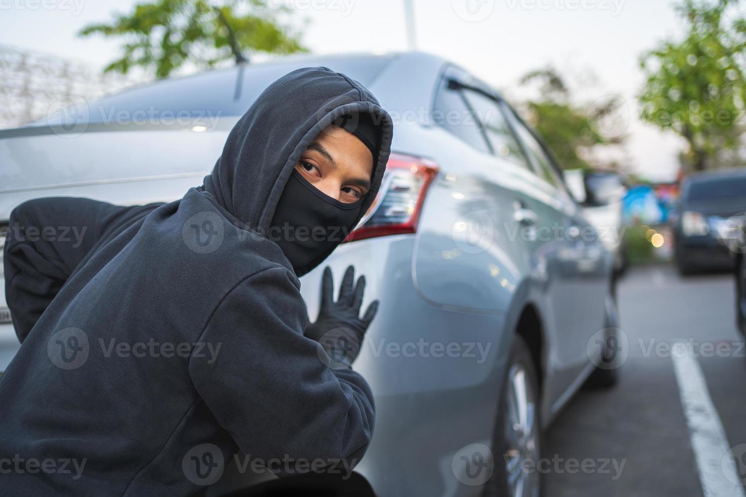 A thief with a robbery mask trying to steal an autobmobile photo