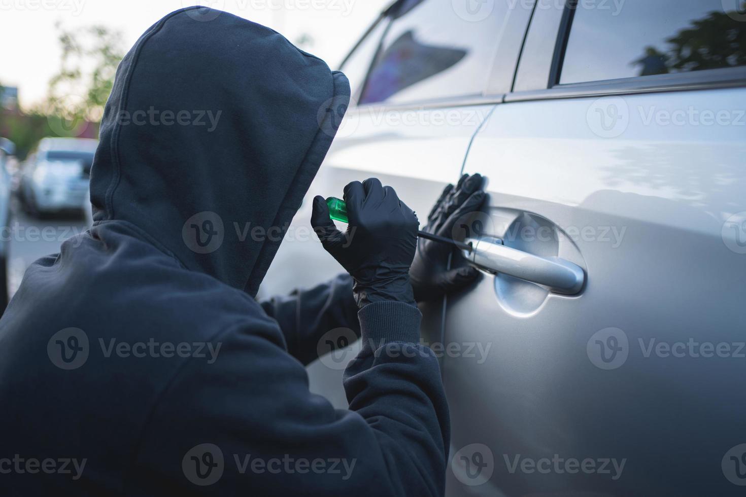 Man in black clothes with a screwdriver. He tried to break into the car. Car theft concept photo