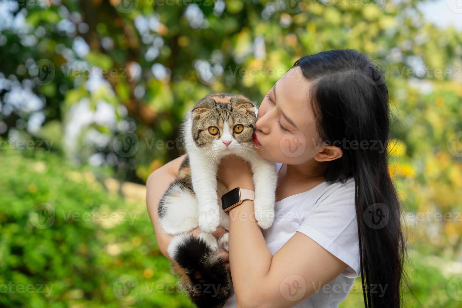 hermosa asiático mujer sostiene un escocés gato con naranja ojos en exterior. mascotas y estilo de vida concepto. foto