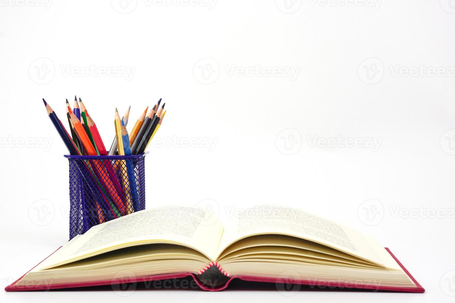 Focus of crayon or colored pencils in box and blur the open book, on white background. Knowledge and education concept. photo