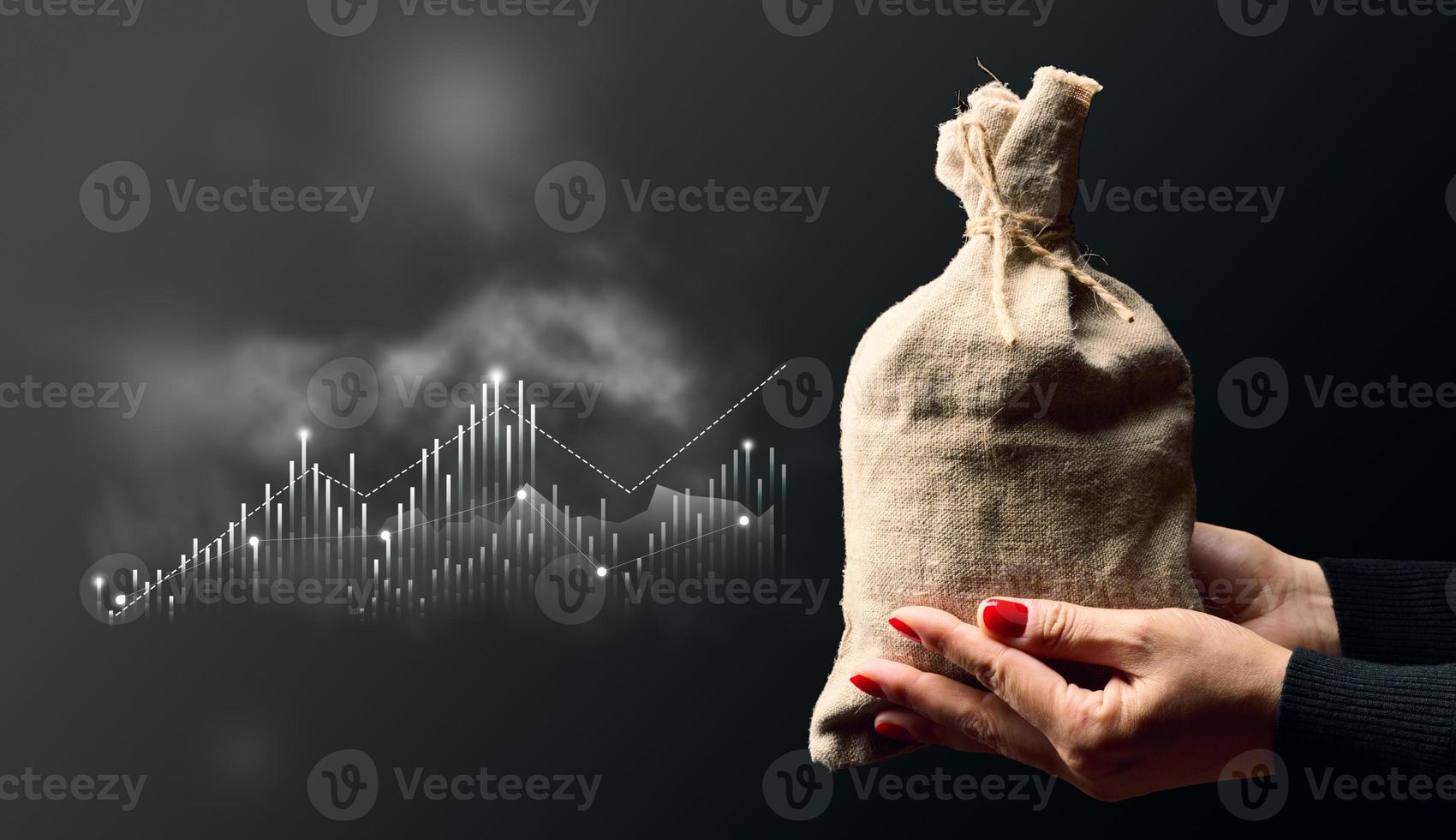 A woman's hands are holding a full burlap sack, symbolizing wealth, and a chart with columns representing business analysis, high profitability photo