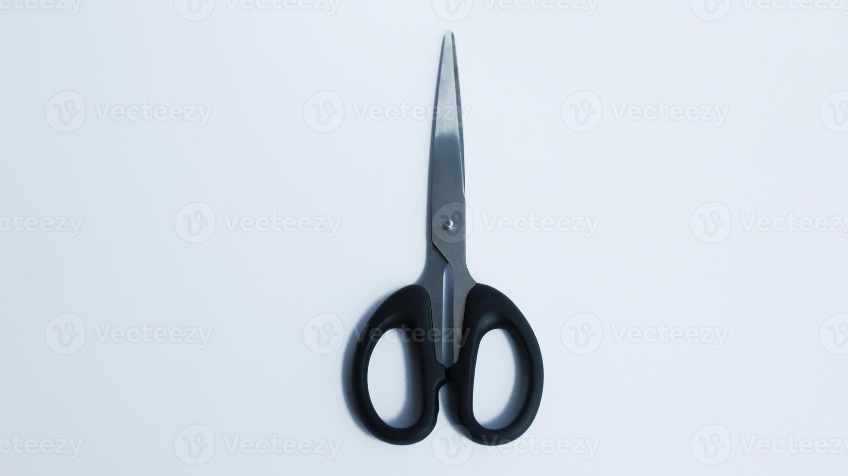 Simple stainless steel with black handler scissor isolated on white photo