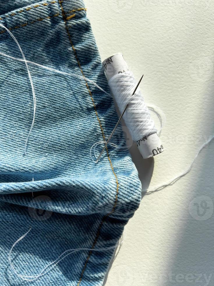 needle and thread. mending jeans photo