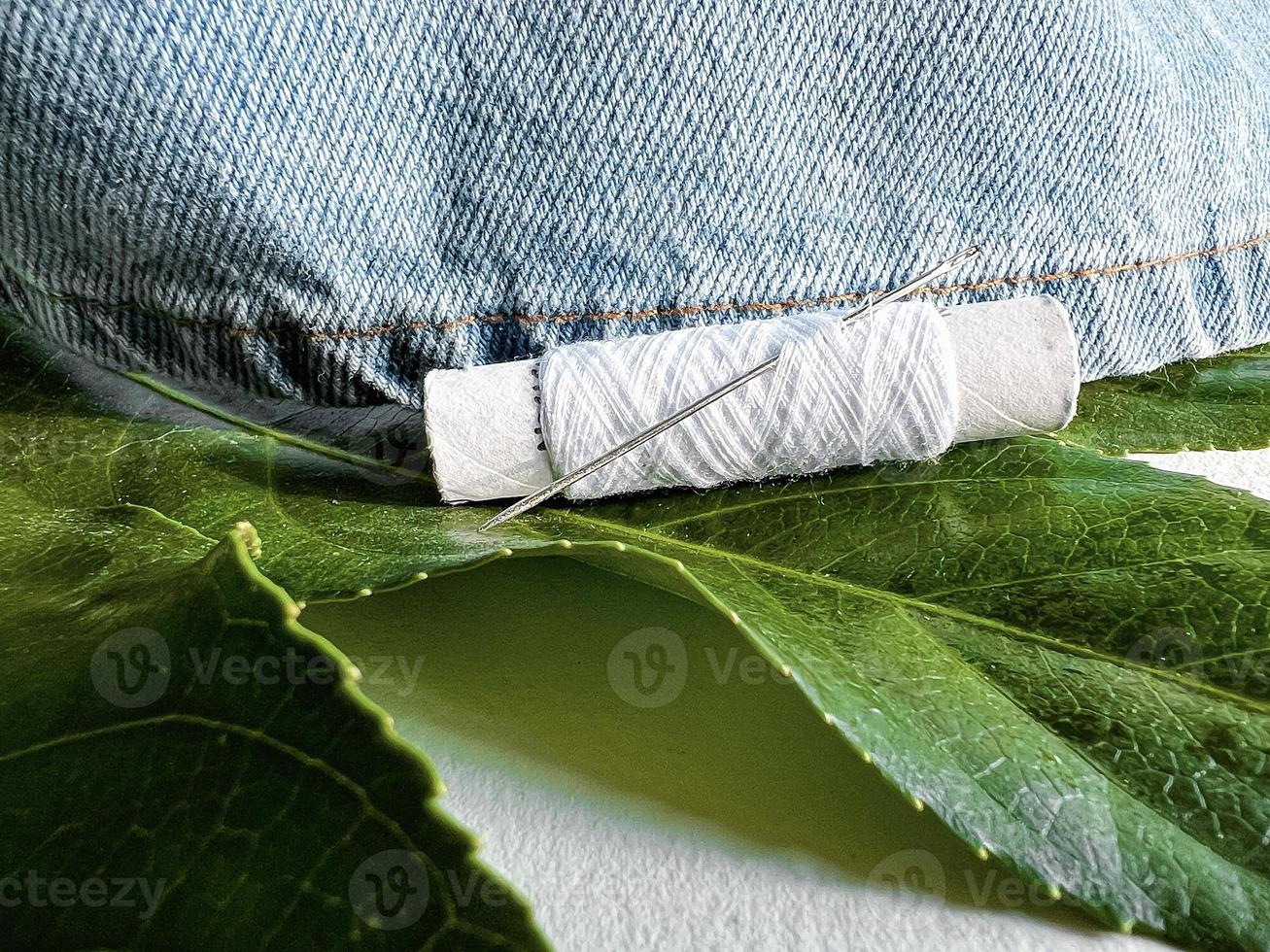 needle and thread. mending jeans. jeans with tropical leaf photo
