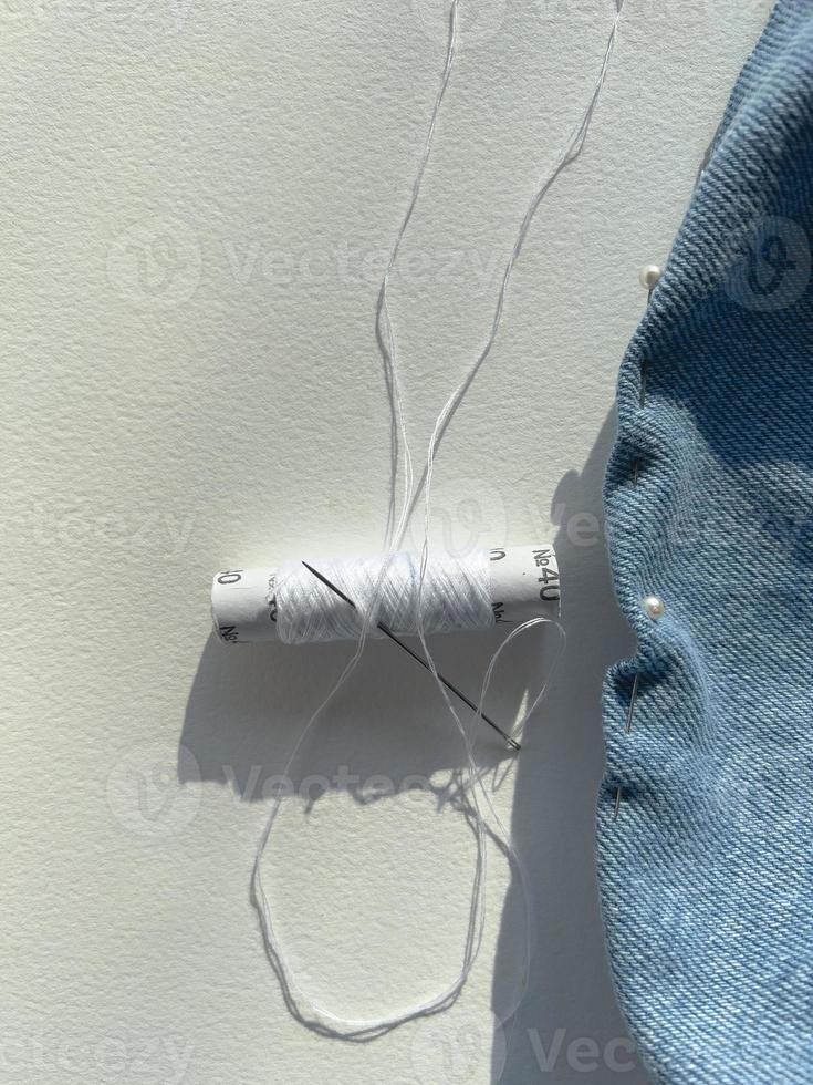 needle and thread. mending jeans photo