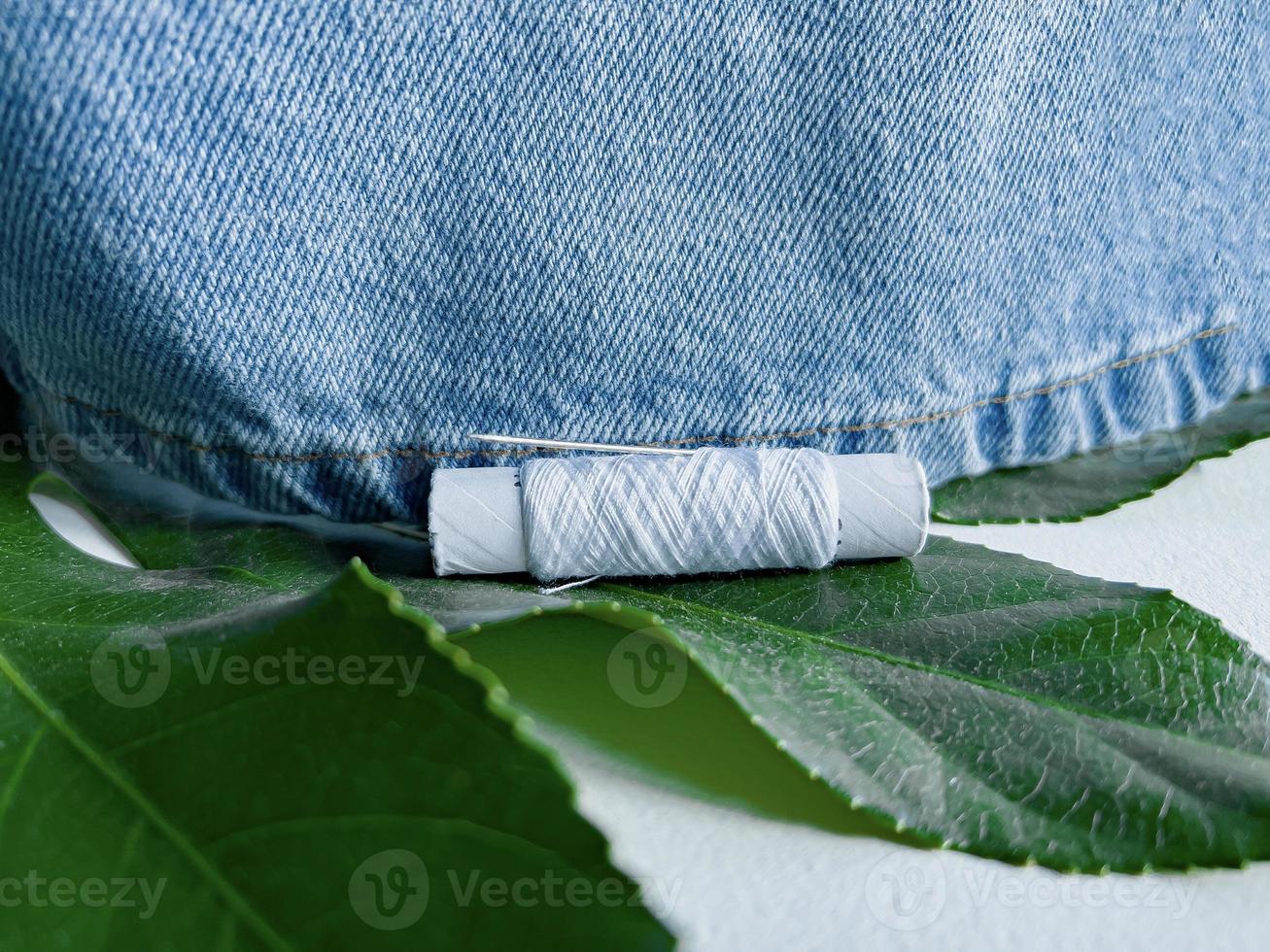 needle and thread. mending jeans. jeans with tropical leaf photo