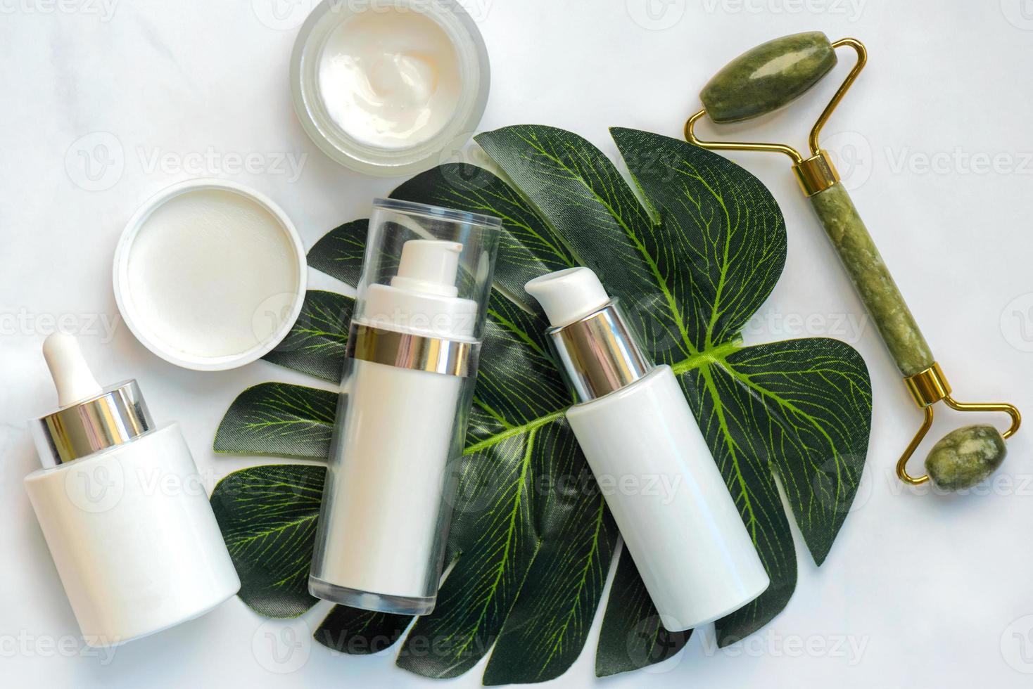 Set of cosmetics and jade massanger roller for skin care with green nature leaf. Skin care products concept photo
