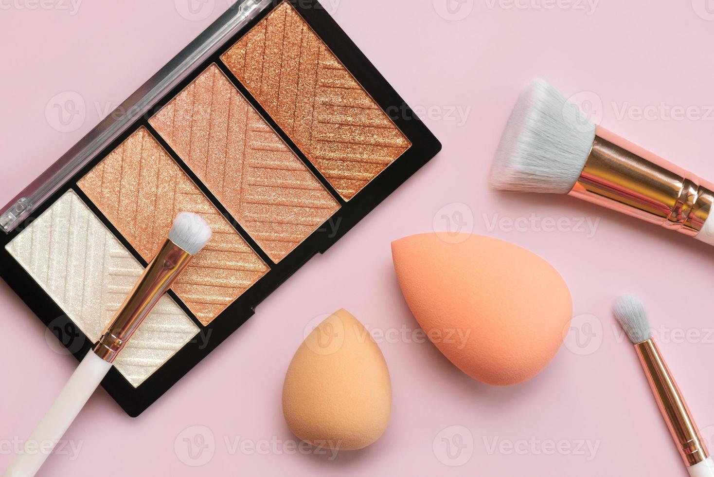 Top view of highlighter palette, makeup sponges and makeup brushes. Beauty and makeup concept photo