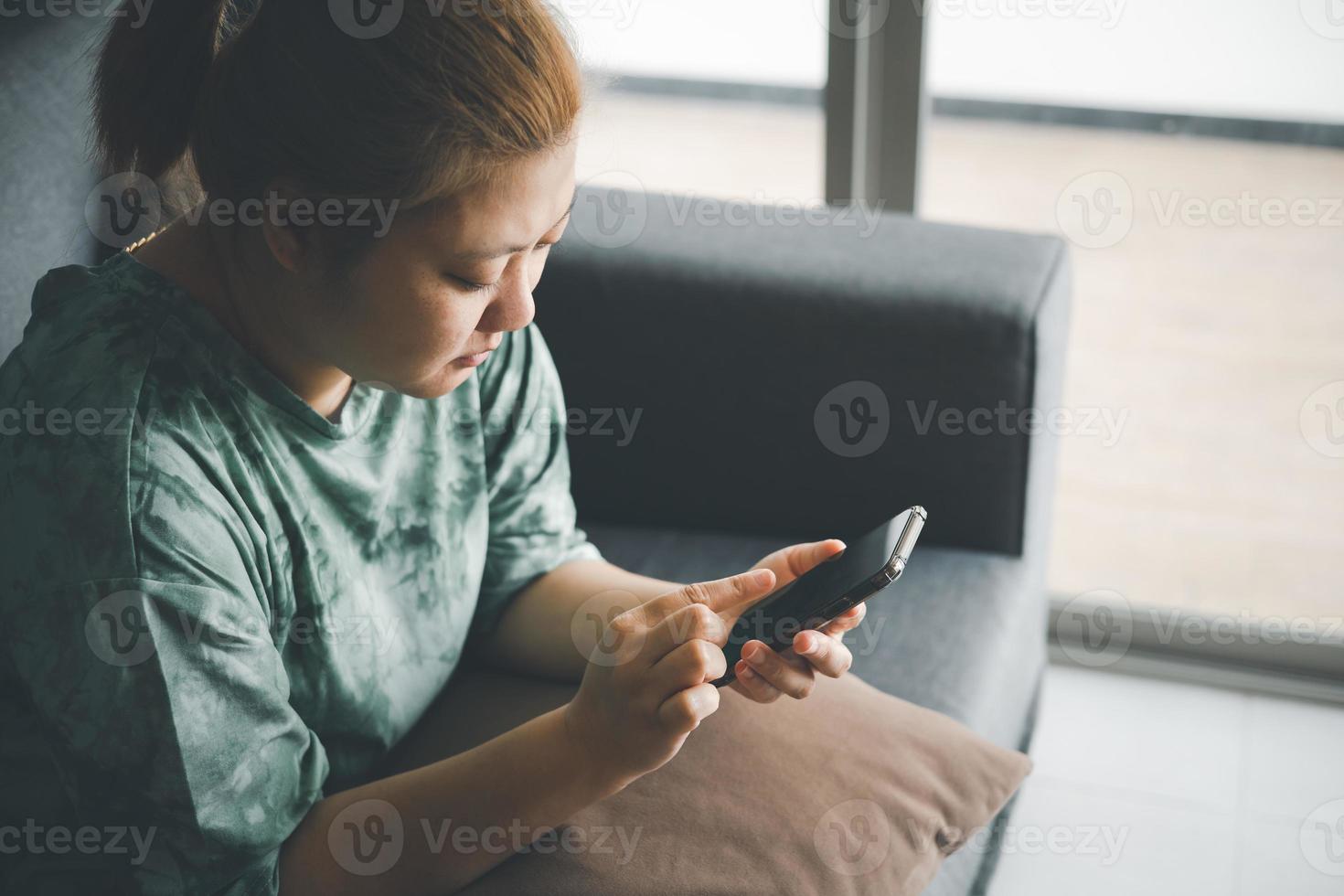 hand of asian woman using smartphone on sofa relaxing and shopping online working from home.use of technology for e-learning,social media,e-commerce photo