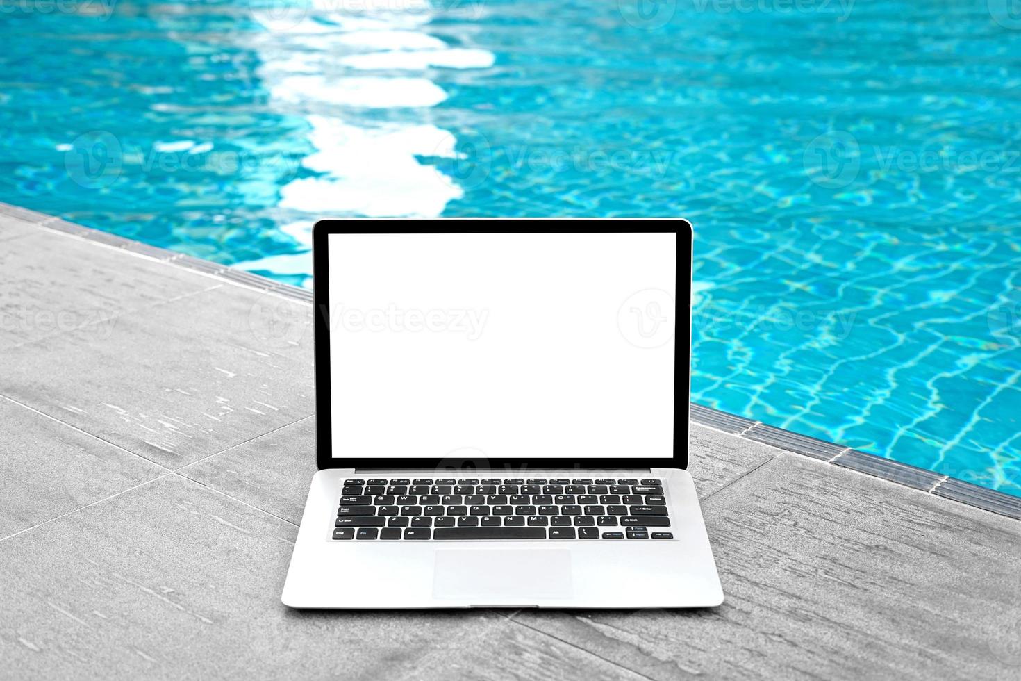 ordenador portátil con blanco pantalla para creativo diseño en piso cerca nadando piscina borde antecedentes. computadora cuaderno con monitor recorte camino para presente aterrizaje página diseño. ordenador portátil computadora burlarse de arriba modelo foto