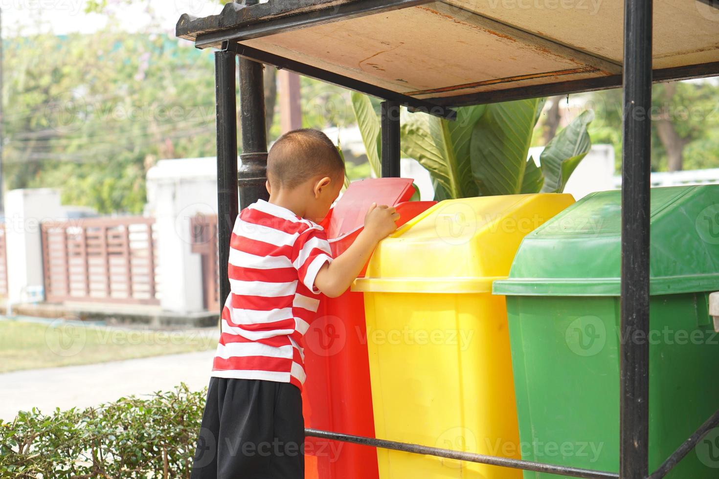 Boy looking at trash cans in the garden photo