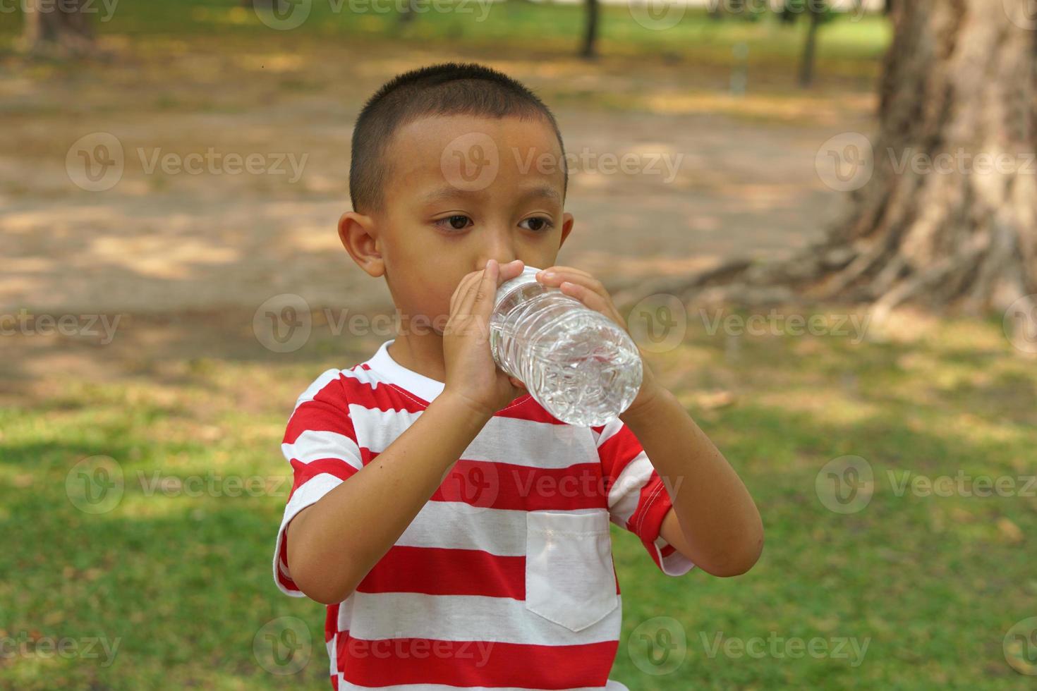 Boy playing drinking water in the park photo