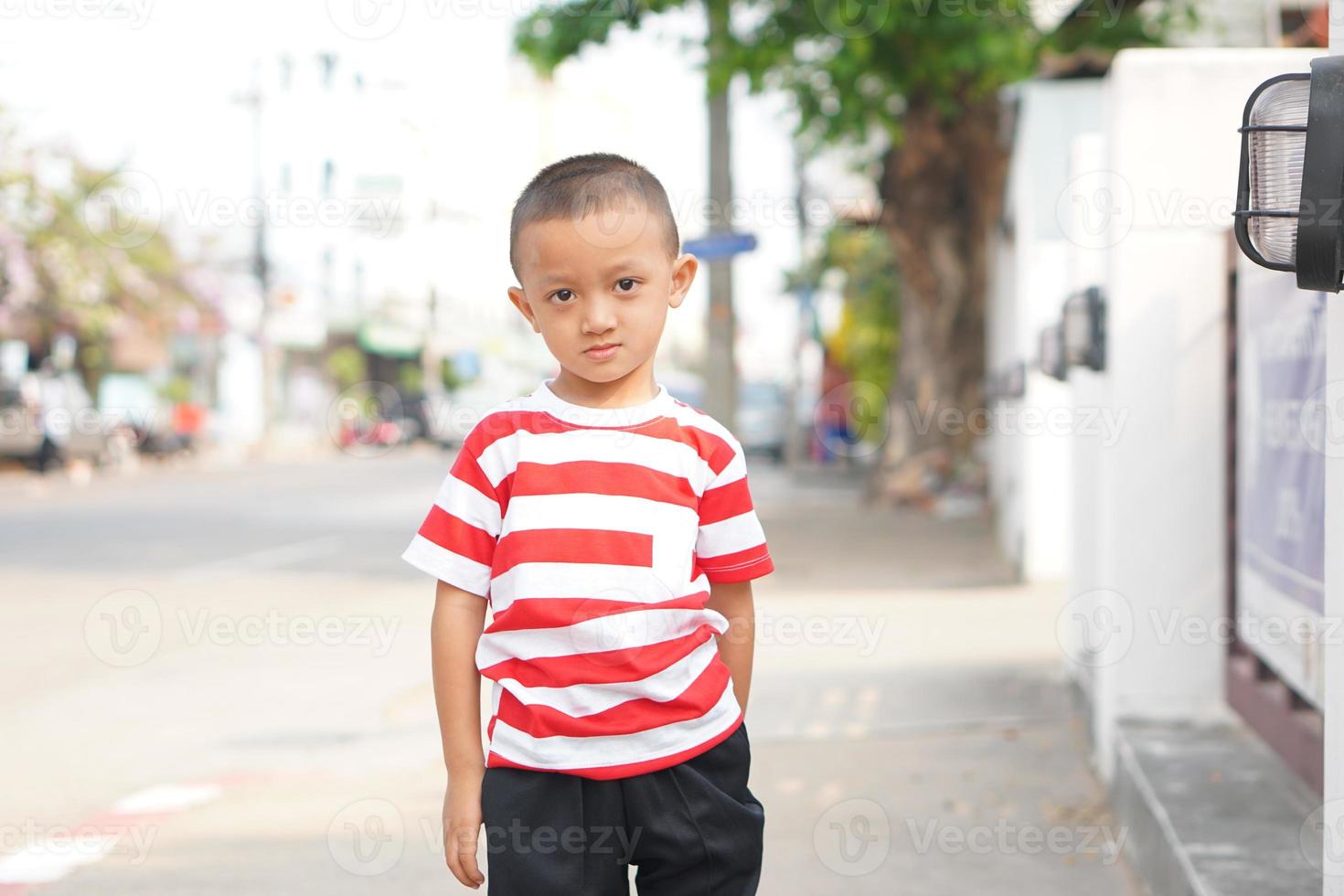 boy stands on the sidewalk on the side of the road. photo