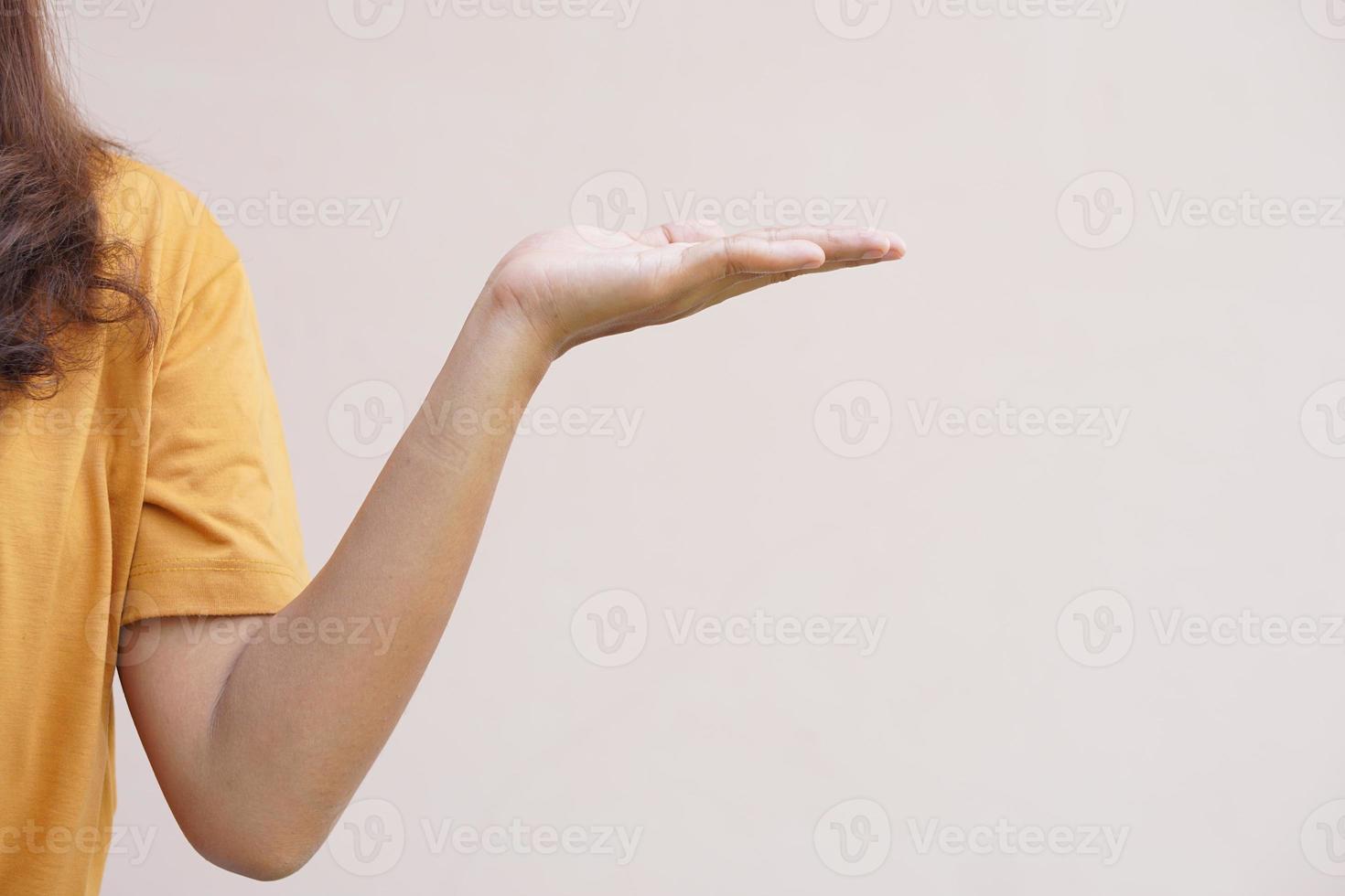 An Asian woman stretches her hand to the side like an empty object on her hand. photo