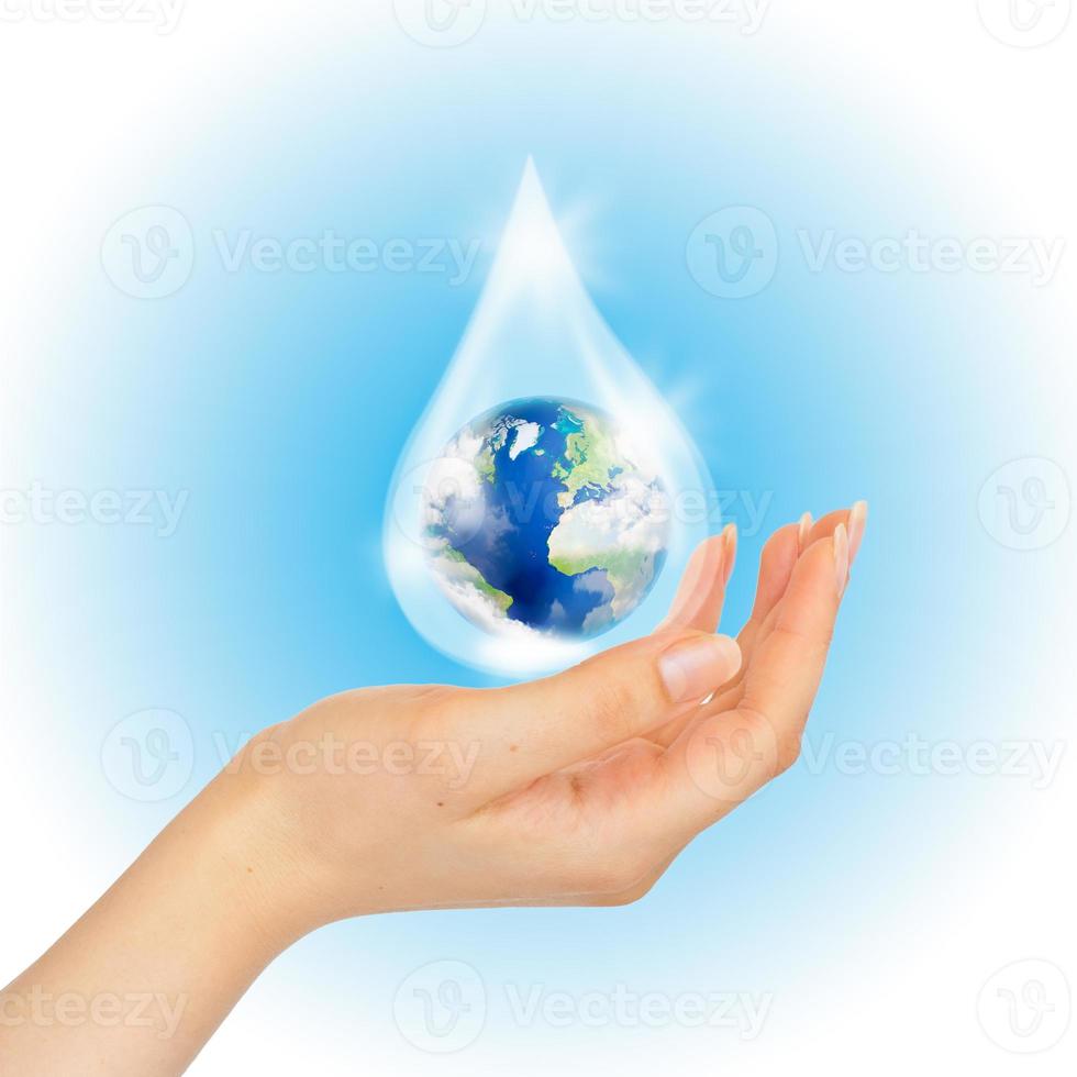 Drop of water with Earth inside and hand on white. photo